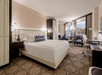 Guest room with one king bed, soft seating, and a well-lit work desk.