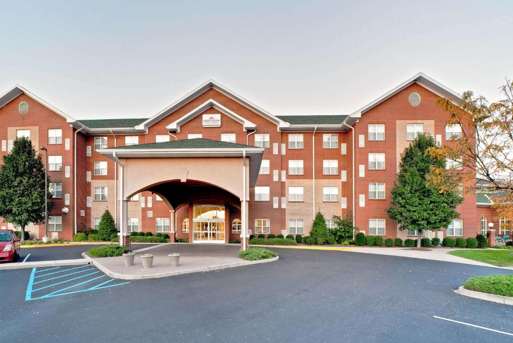 Front view of a multi-story brick building with an arched entrance, ample windows, and surrounding greenery, featuring a blue accessible parking spot in the foreground.