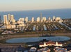 Aerial view of Hallandale Gulfstream with high-rise buildings, residential areas separated by water canals, and a racetrack in the foreground, near the ocean.