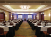 Meeting facility with long tables, chairs and a white projector screen.
