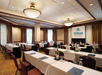 Meeting facility with long tables, chairs and a white projector screen.