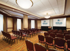 Meeting facility with long tables, chairs and a white projector screen.
