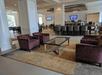 A lounge area with four purple chairs and a glass coffee table with a bar and other seating areas in the background.