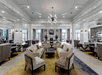 A large bright lobby with several seating options, large floor to ceiling windows, and an abstract chandelier