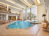 Indoor pool with sun loungers surrounded by floor-to-ceiling windows overlooking the outdoors.