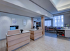 Hotel lobby area with a reception desk and a small market section displaying snacks and drinks. The space features light wood and neutral-colored decor.