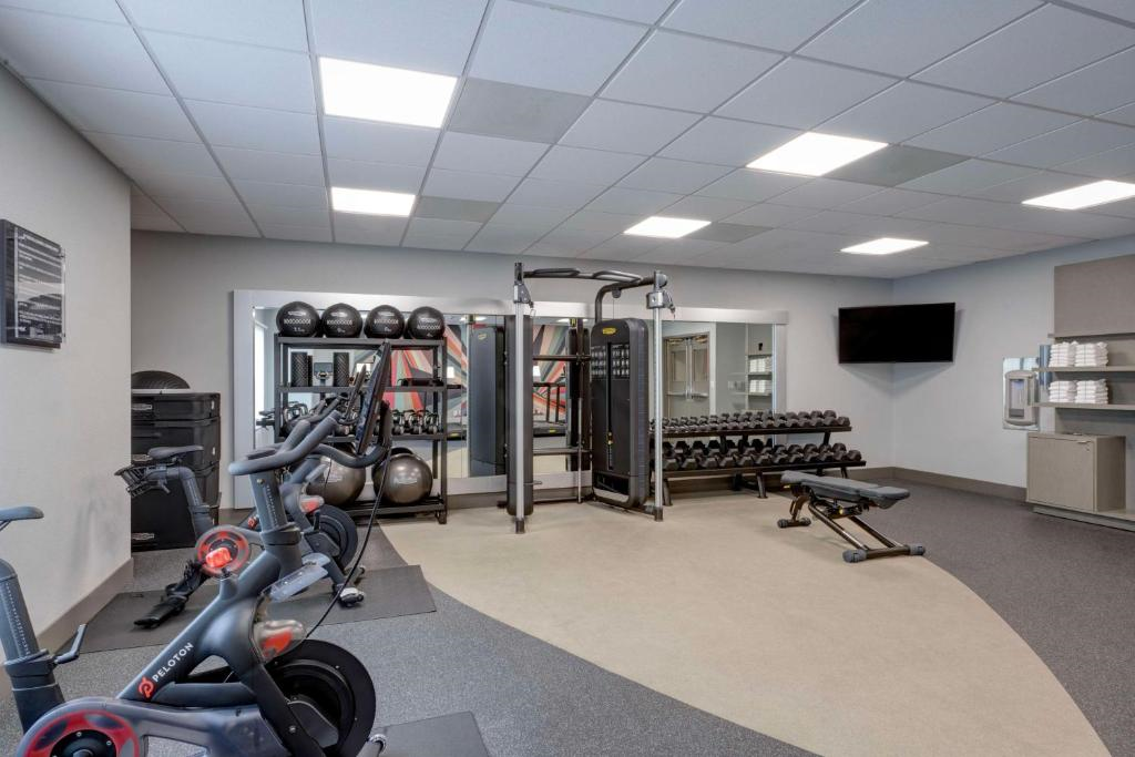 A gym with exercise bikes, a cable machine, free weights, benches, and a TV on the wall.