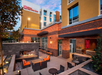 Outdoor seating area of a Hilton Garden Inn, featuring chairs, tables, and a fireplace, with the hotel's sign visible on the building in the background.