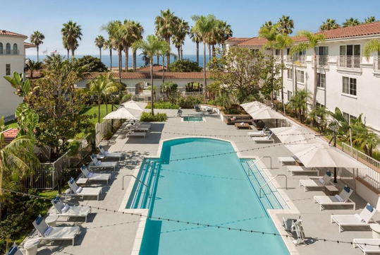 Outdoor pool, tub, and sun loungers with umbrella.