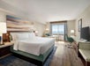 A king bed, ocean view, bedside lamps, seating area, desk, and TV in a guest room.