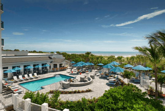 View of the outdoor pool with sun loungers at Hilton Garden Inn Cocoa Beach-Oceanfront, FL.