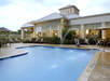 Outdoor swimming pool with lounge chairs and umbrellas, adjacent to a building with large windows and a metal roof.