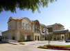 Exterior view of a hotel building with a large entrance, American flag, multiple windows, and a parking lot.