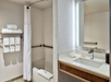 Modern bathroom with a bathtub and shower, white towels on a rack, and a sink with a large mirror.