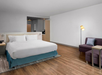 One king bed, seating area, and sofa inside a guest room.