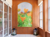 A hallway with wooden walls features a large floral artwork and two candle lanterns on the floor.