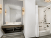 Accessible guest bathroom with sink, mirror, and shower/tub combo.