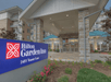 Entrance of Hilton Garden Inn with a blue sign displaying the address 2481 Teaster Lane. The building has stone pillars and a peaked roof.