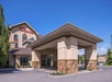Exterior view of a Hilton Garden Inn with a stone and stucco facade, a covered entrance, and clear blue sky in the background.