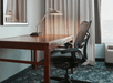 Well-lit work desk with ergonomic chair inside a guest room.