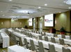Spacious meeting room with long tables, chairs, whiteboards, and a podium.