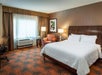 One king bed, bedside lamp, seating area, desk, and air condition in a guest room.