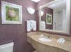 Bathroom with a large mirror, sink, hand towels, and framed flower art on a purple textured wall.