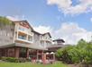 Exterior view of a Hilton Garden Inn hotel with a landscaped garden and blue sky.