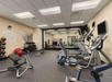 A gym room with exercise bikes, treadmills, a bench, weights, and a large mirror on the wall.