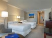 Two queen beds and bedside lamps inside a guest room.