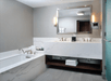Bath tub and well-lit vanity area with free toiletries inside a private bathroom at Hilton Marco Island Beach Resort and Spa, FL.