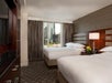 Two double beds, an expanded window, and a flat-screen TV inside a guest room.