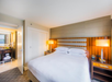 One king bed, desk lamps, alarm clock and telephone inside a guest room.