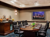 Meeting facility with a large table, executive chairs, flat-screen TV and snacks.