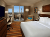 One king bed, flat-screen TV, work desk, and a private balcony inside a guest room.