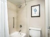 Combined shower/tub with grab bars inside a guest bathroom.
