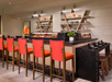 A modern bar area featuring red cushioned chairs, a black countertop, and decorative shelves with tableware and vases.