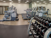 A gym with treadmills, stationary bikes, and a rack of dumbbells.