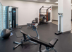 A gym room with weight machines, exercise balls, and benches. A scale is positioned near the entrance.