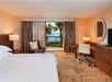 One bed, seating area, work desk & chair, and balcony inside a guest room.
