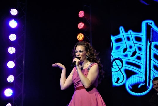 Woman wears a pink dress while singing during Hit Parade at The Grand Majestic Theater