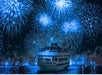 A boat named "Atlantic Star" sails on water at night, with large blue fireworks lighting up the sky in the background.