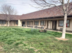 Motel building with a sloped roof, two trees, and a grassy courtyard. A lawn mower is parked near the center.