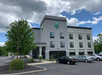 Hotel building with three stories, Holiday Inn logo, and several parked cars in the lot under a partly cloudy sky.