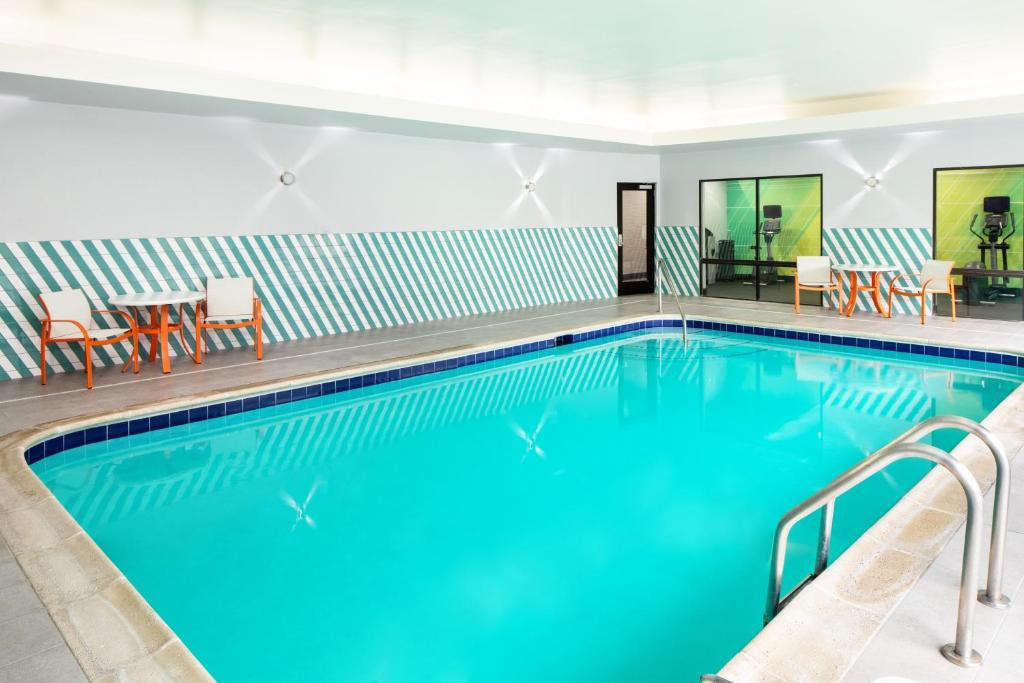 Indoor swimming pool with two tables and chairs along the walls, featuring a blue and white striped design.