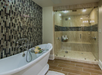 A luxurious bathroom featuring a deep soaking tub and a spacious glass-enclosed walk-in shower with built-in bench seating.