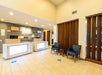 Hotel lobby with a modern design, featuring a reception desk and seating area. There are blue social distancing markers on the light-tiled floor. Wooden accents decorate the walls.