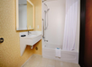 Bathroom with a wall-mounted sink, mirror, and a bathtub-shower combo with a curtain. The walls have a patterned design, and a towel is placed on the bathtub edge.