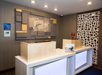 Modern hotel reception area with two desks, illuminated panels, and a decorative wall. Plaque displays "Holiday Inn Express.