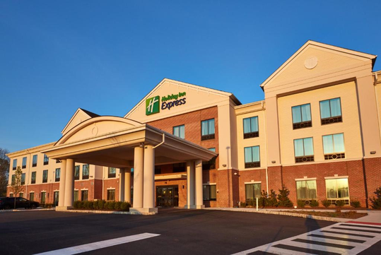 Three-story hotel building with brick and cream facade, featuring a covered entrance and a Holiday Inn Express sign.
